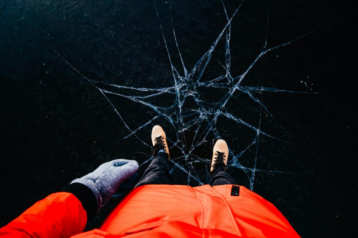 Person standing on dark, cracked ice.